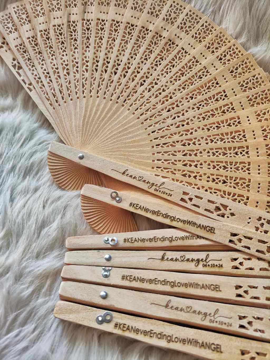 Sandalwood hand fan with laser-engraved custom design, ideal as a wedding souvenir.